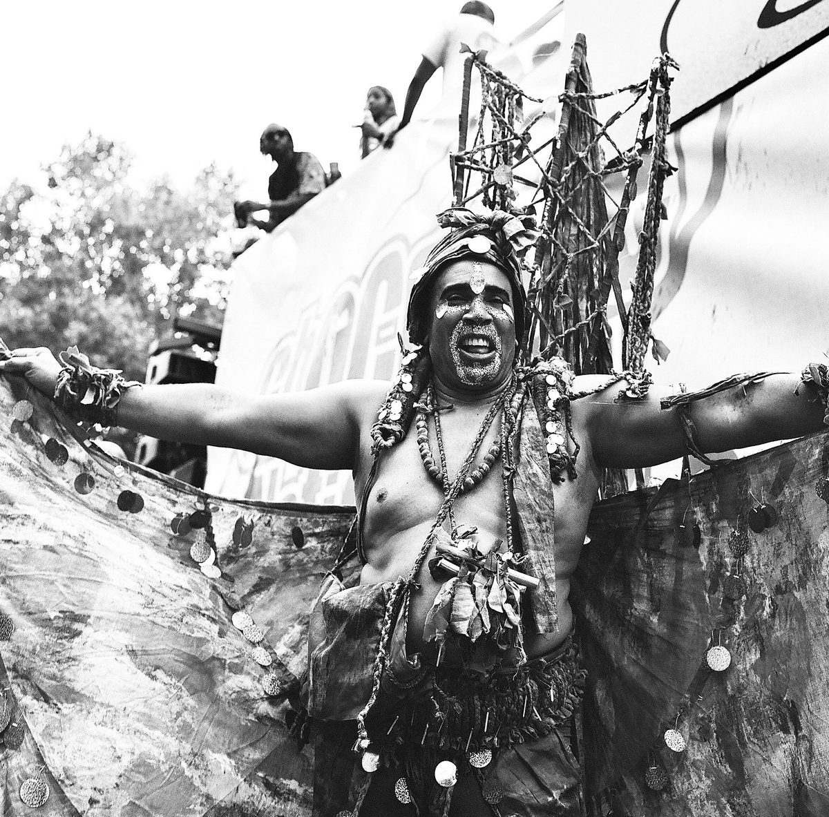 Carnival performer in costume with arms spread wide, black and white