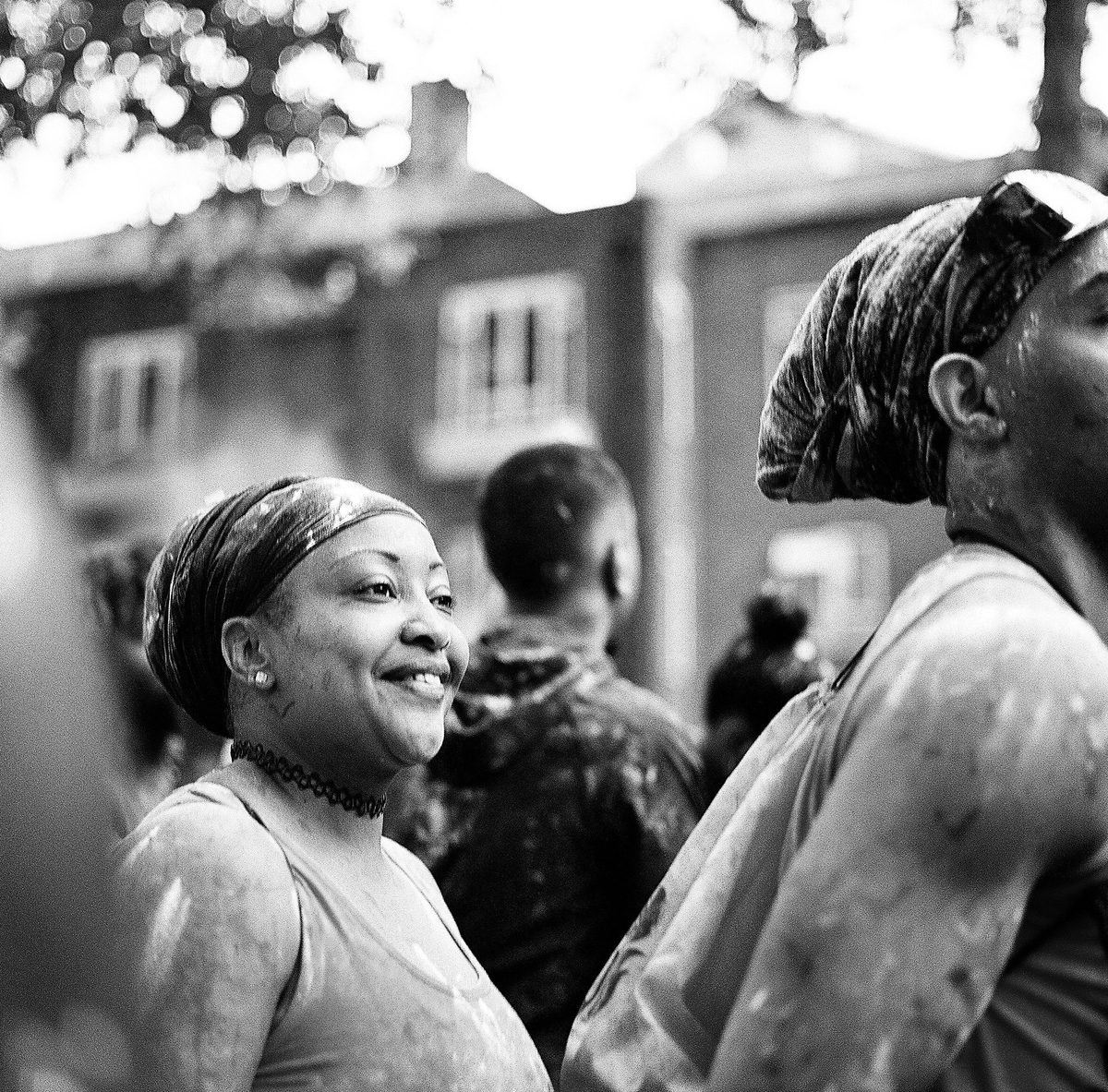 Woman smiling in a paint-splashed carnival crowd, black and white