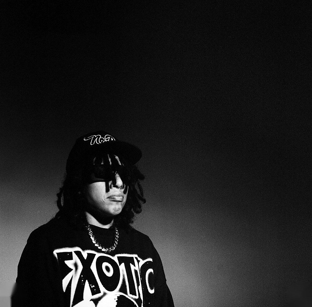 Artist in a cap and Exotic sweatshirt against a dark gradient, black and white