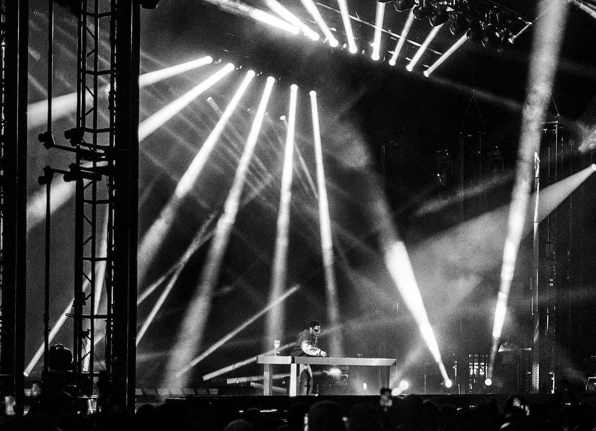 DJ at the decks under a wall of white light beams