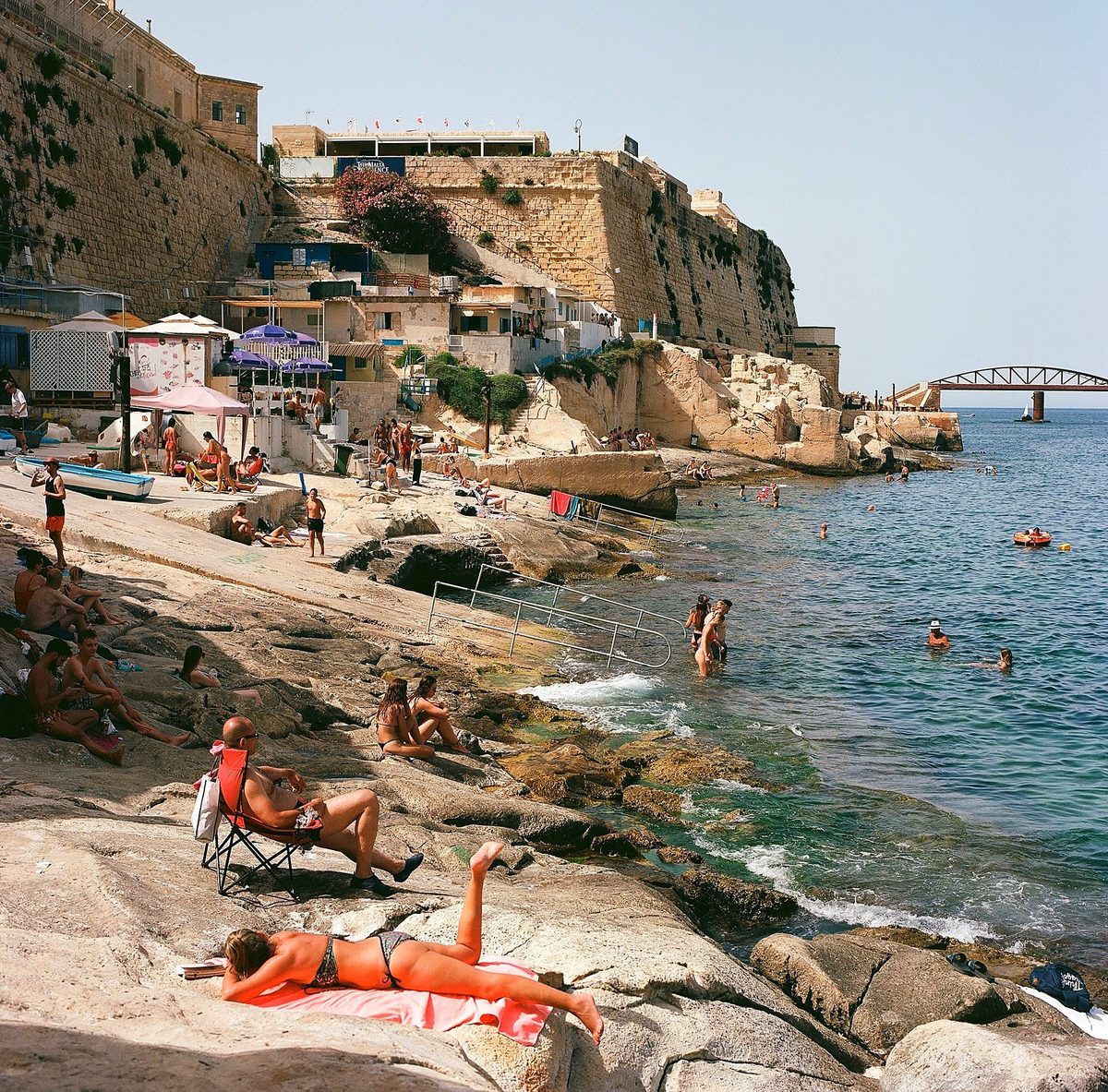 Swimmers and sunbathers below fortress walls