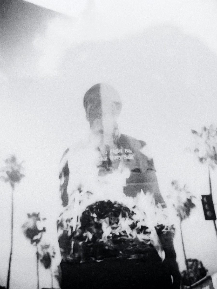 Double exposure of a figure dissolving into palm trees and sky, black and white