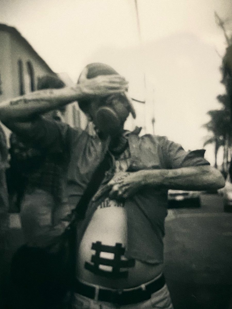 Man in a gas mask and bandana shielding his eyes, sepia